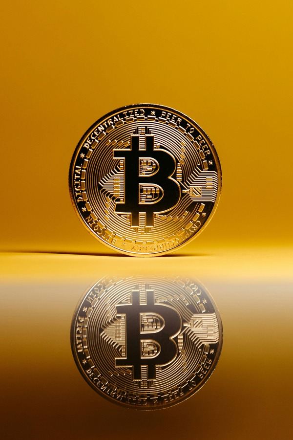 Bitcoin coin reflected on a glossy golden surface