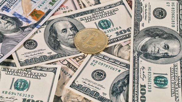 Gold crypto coin lying on a pile of US dollar banknotes