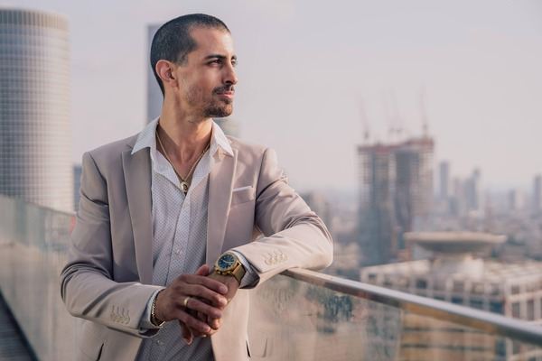 Man in a suit on a balcony overlooking the city skyline