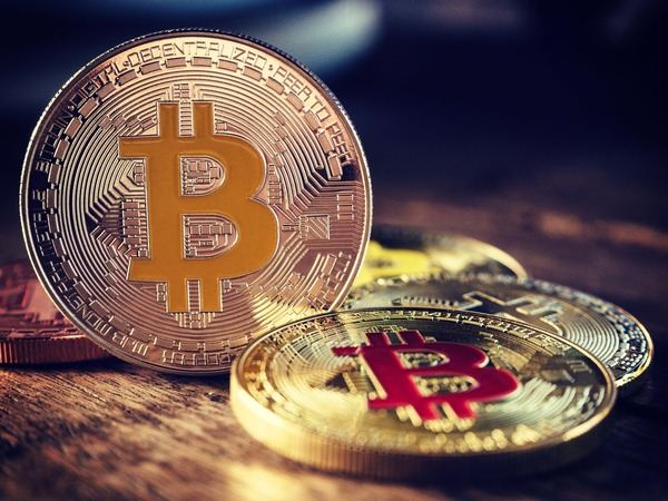 Bitcoin coins lit by warm light on a dark background