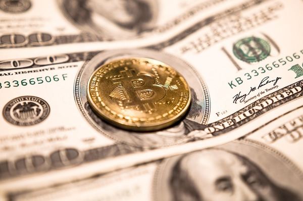 Gold Bitcoin coin on top of US dollar bills