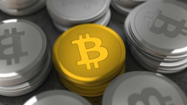 Gold Bitcoin coin resting on a stack of silver coins