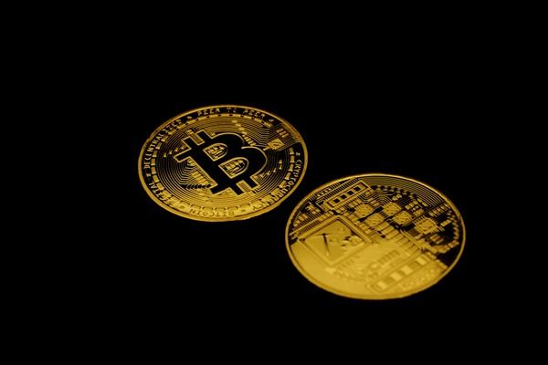 Two gold Bitcoin coins on a black background