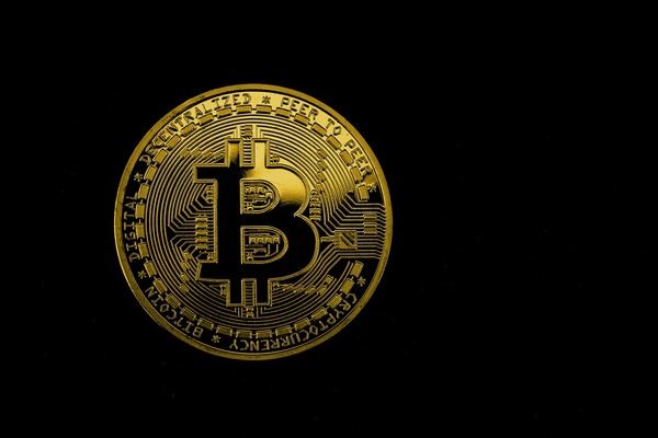 Single gold Bitcoin coin on a black background