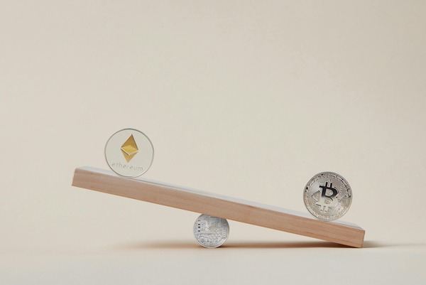 Ethereum and Bitcoin coins balanced on a wooden seesaw
