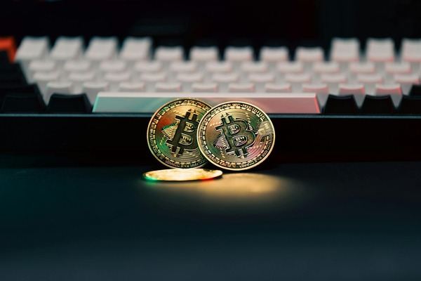 Bitcoin coins standing on a keyboard in red light