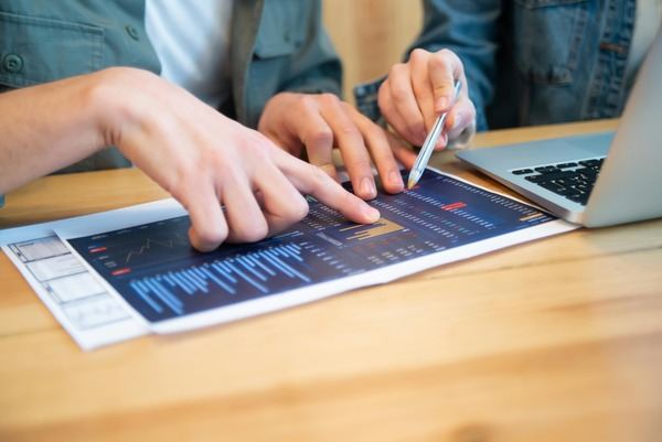 Hands working with charts on a laptop and a tablet