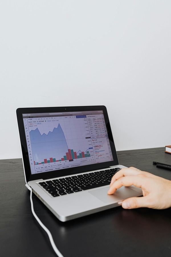 Person using a laptop with a market chart on screen